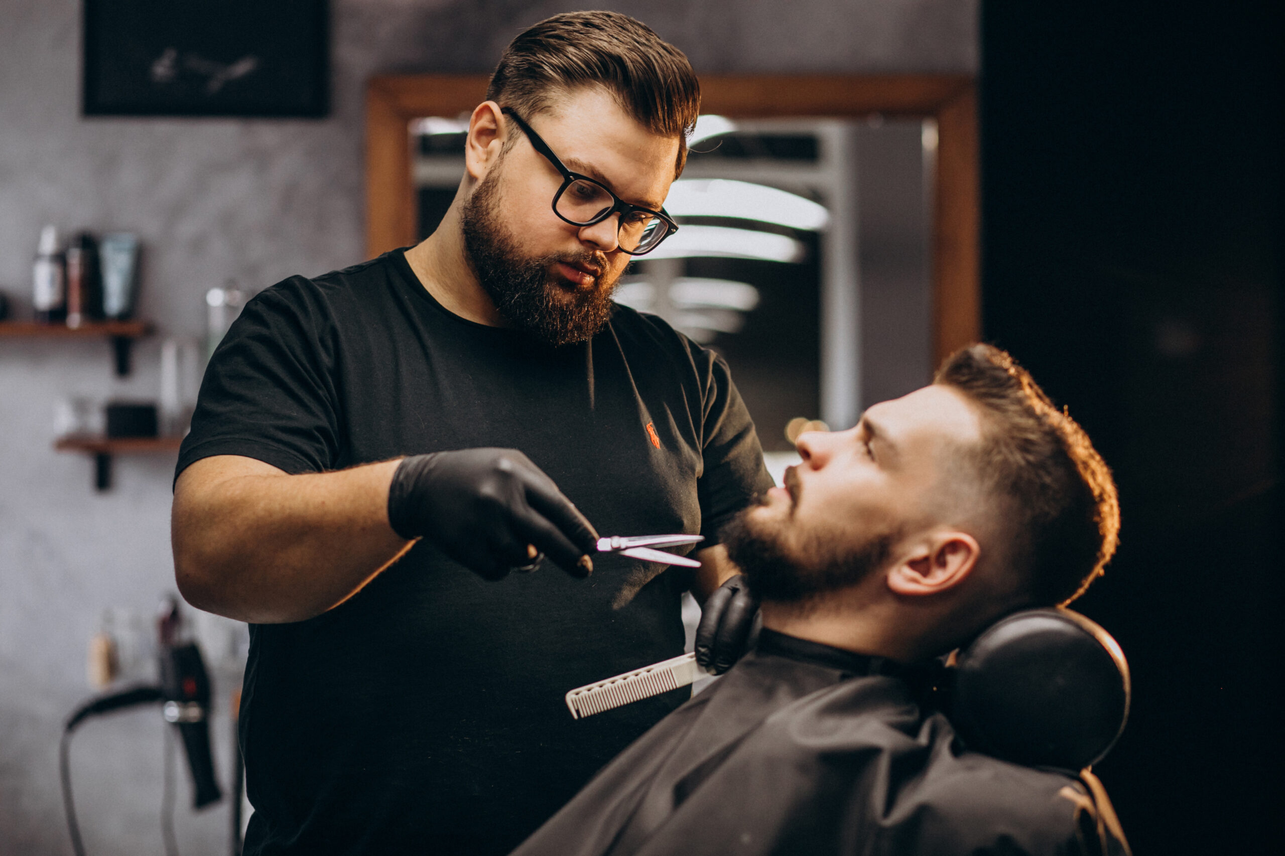 Handsome man cutting beard at a barber shop salon